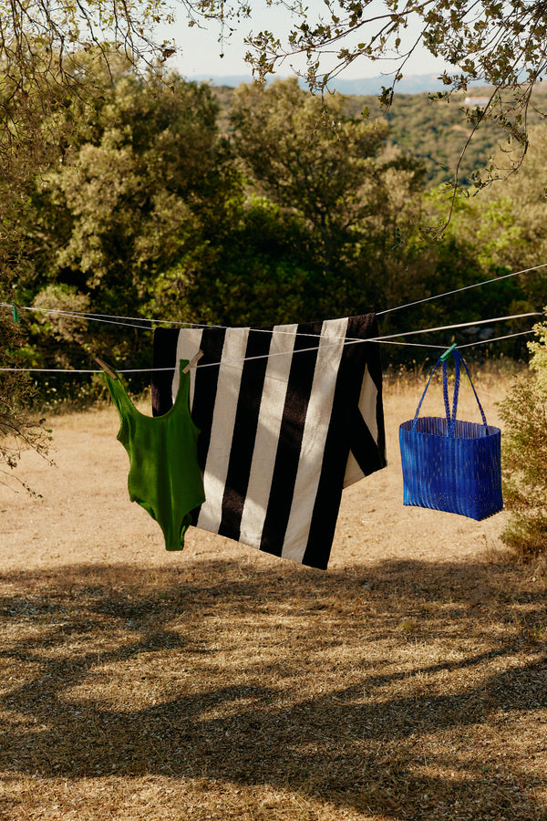 Clothing hanging on a clothesline with a blue basket in a natural setting